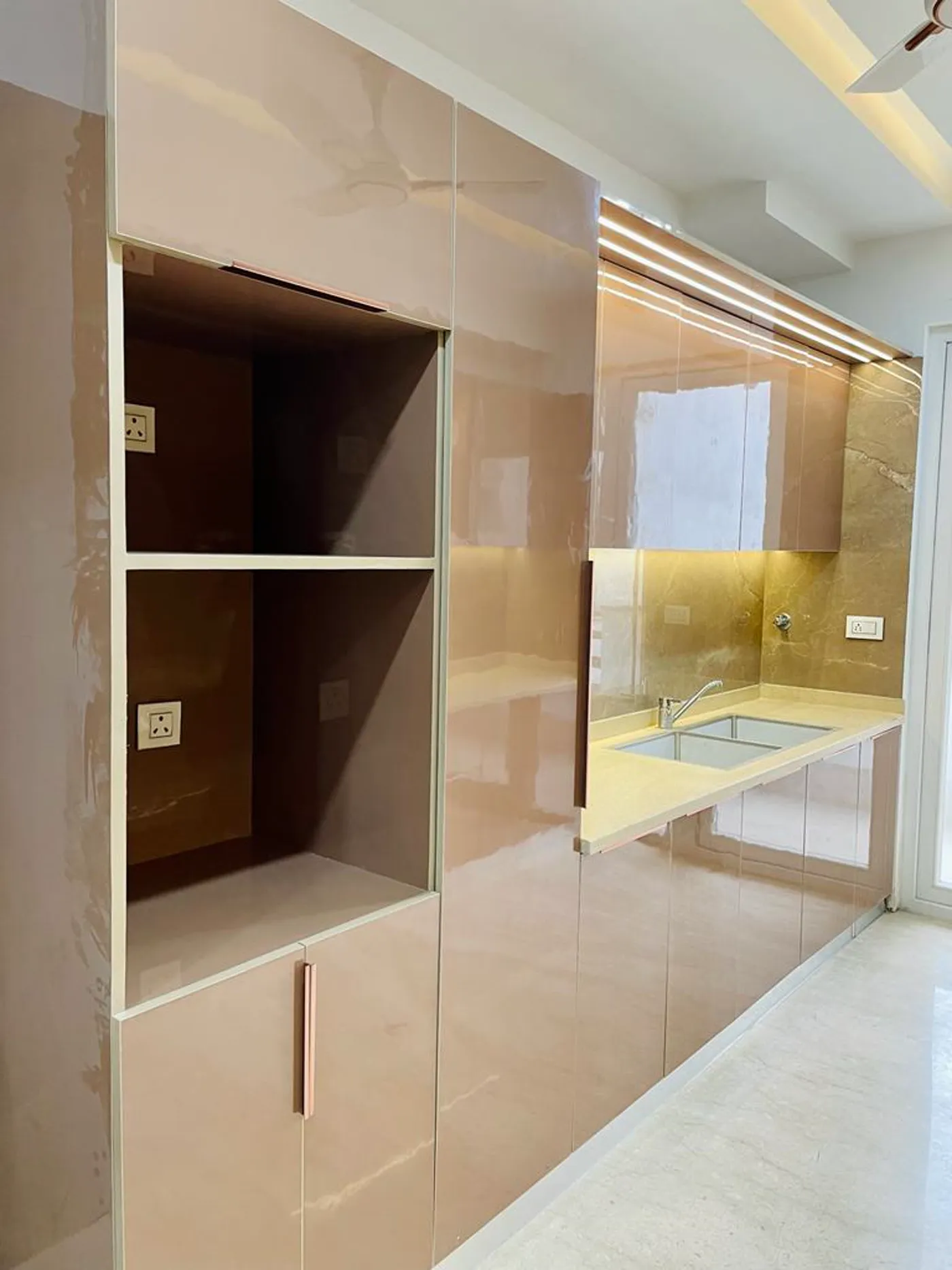 Modular kitchen with blush pink high-gloss cabinetry and integrated sink