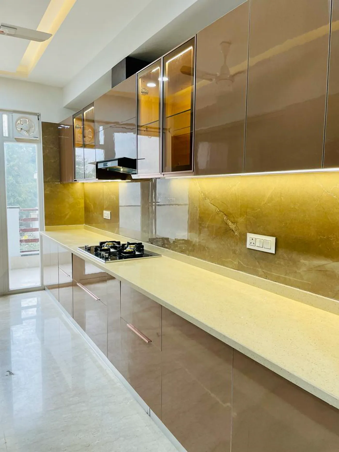 Long modular kitchen run with warm gold stone backsplash and mocha cabinetry