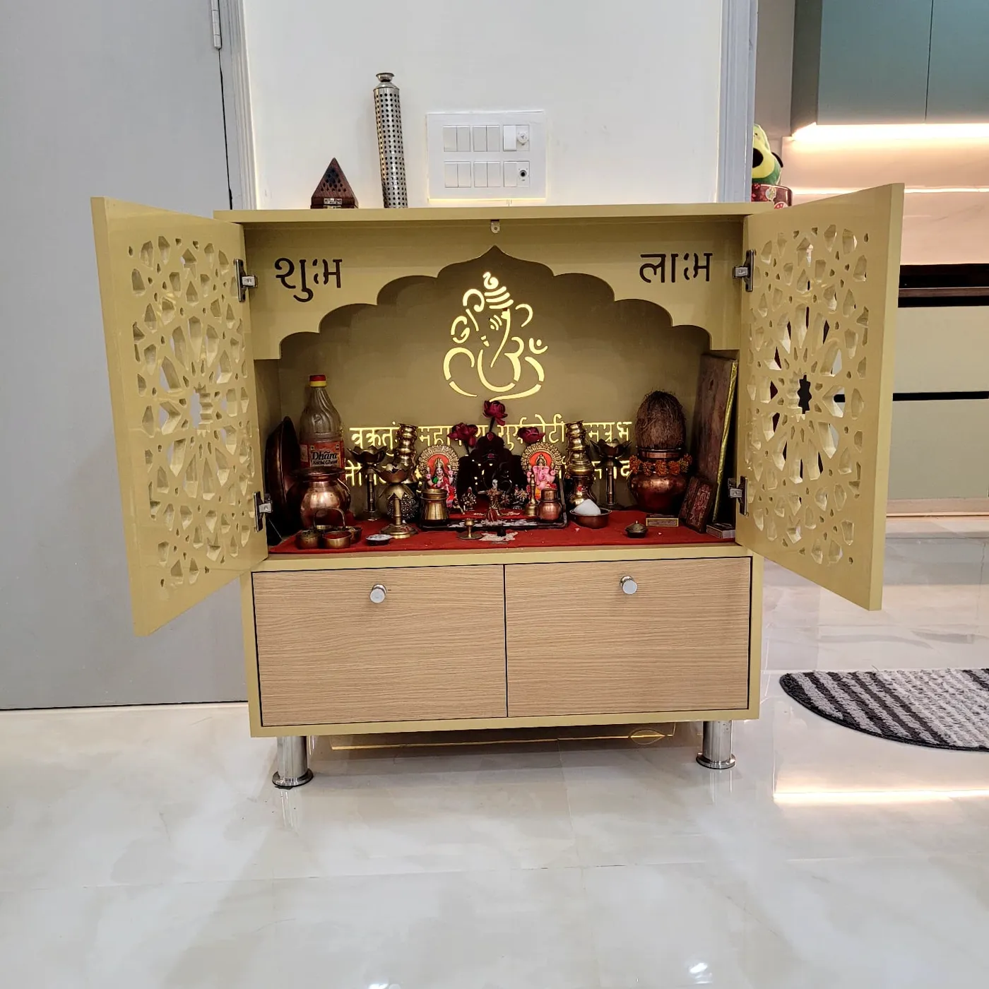 Custom-built backlit pooja unit with intricate jaali-cut doors and Ganesha motif
