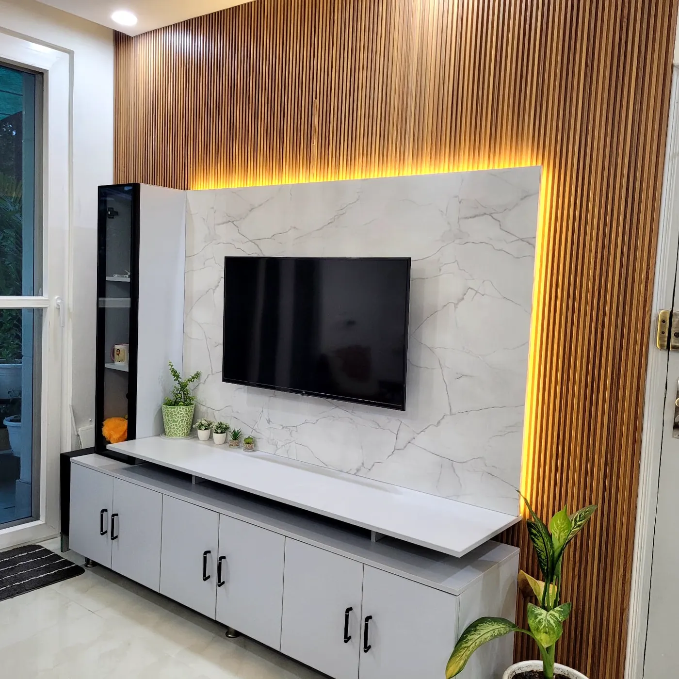 TV unit with marble-finish panel and warm-lit wood slat wall